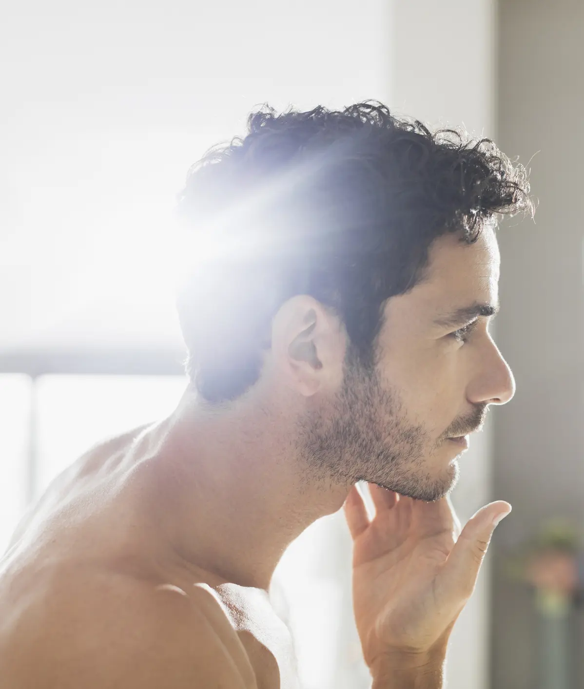 Man checking beard in bathroom mirror Cosmetic Breast Surgery and Enhancement in Daytona Beach, FL