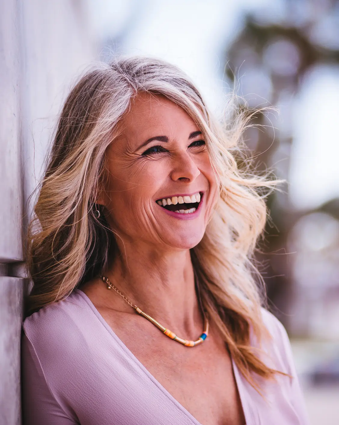 Beautiful stylish senior woman laughing leaning against wall outdoors Cosmetic Breast Surgery and Enhancement in Daytona Beach, FL