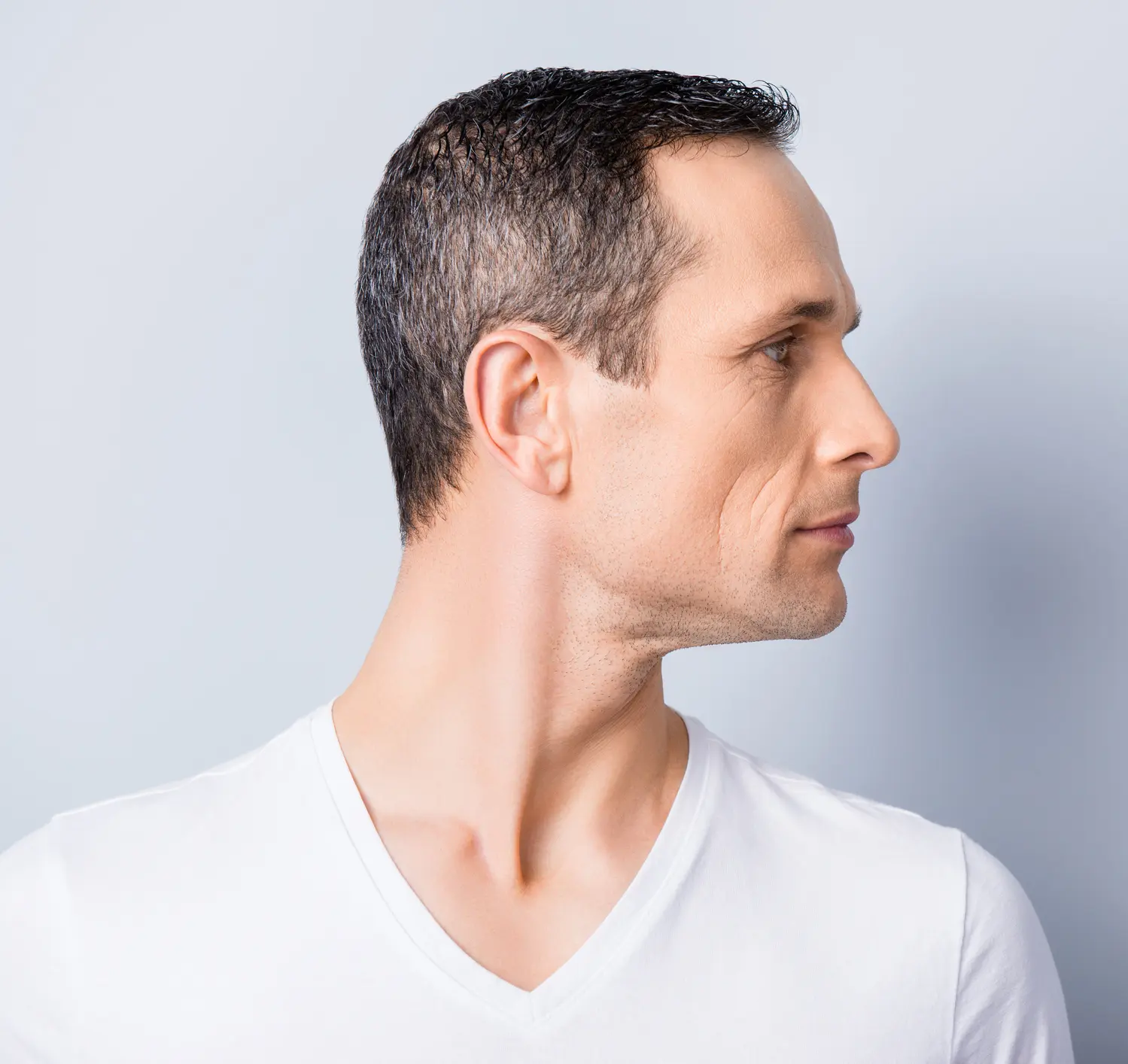 Portrait with copy space, empty place for product, advertisement of attractive, stylish man with turned profile face to the side, having perfect ideal oiled, dry skin, isolated on grey background Cosmetic Breast Surgery and Enhancement in Daytona Beach, FL